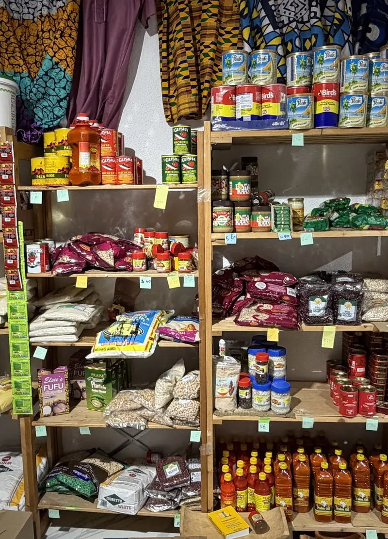 Regal im Laden mit afrikanischen Zutaten wie Mehl, Bohnen, Konserven und Palmöl.