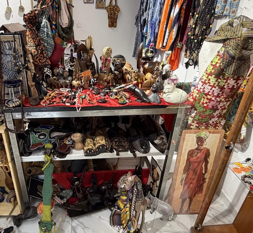 Holzfiguren, Masken, Ketten und Taschen in einem Regal im Laden.